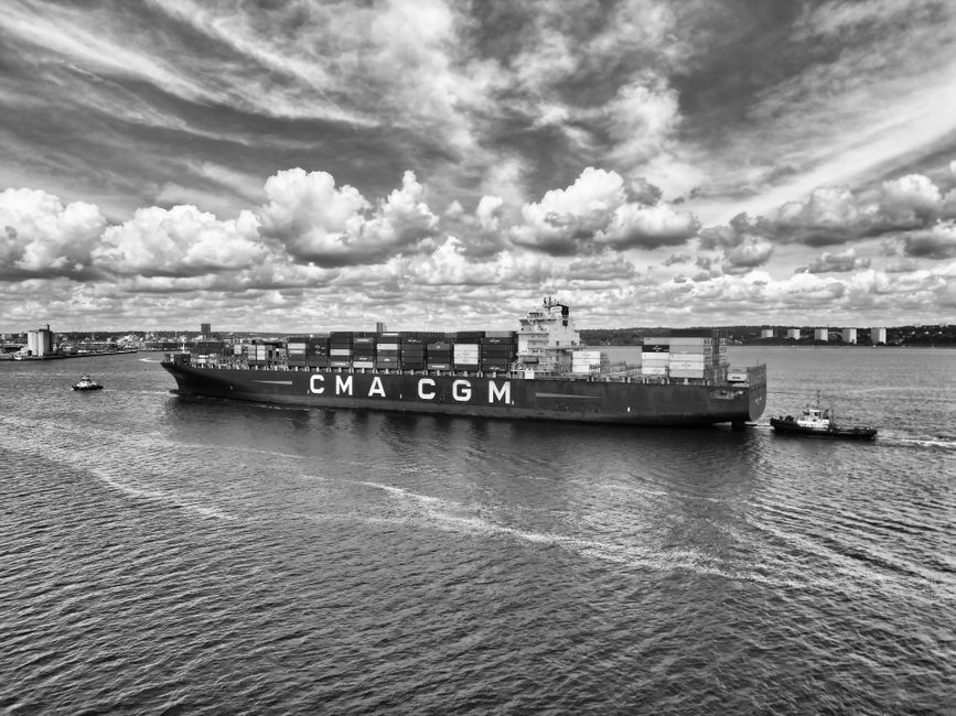 Monochrome photo of a CMA CGM container ship in Southampton waters under a dynamic sky.
